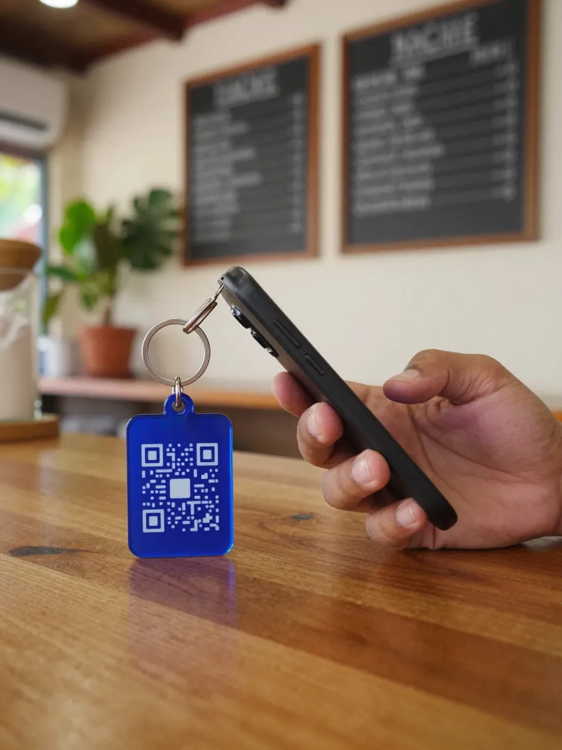 Cliente escaneando con su celular el llavero con QR en el mostrador de una taquería